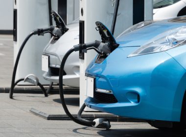 Electric cars being charged at a station. One is blue.