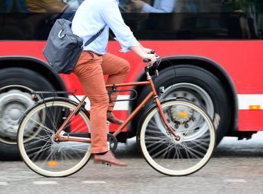 Bicycle commuter riding next to a bus.