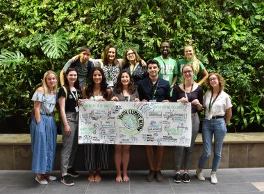 Students holding a YACC sign in front of a green wall