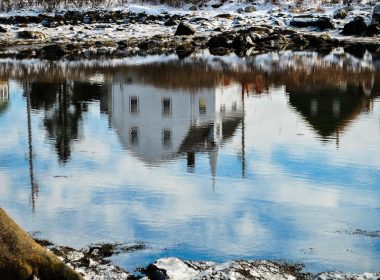 (Photo: a reflection of a village in a body of water)